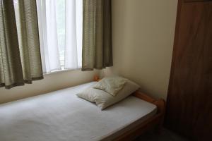 - un petit lit dans une chambre avec fenêtre dans l'établissement Family Vendégház, à Balatonszárszó