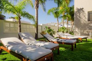 a group of chaise lounges in a yard with palm trees at La Casa del Mar in Chiclana de la Frontera