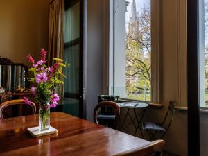 a vase of flowers on a wooden table with a window at Bell Hill Apartments in Dunedin