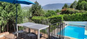 a patio with a table and an umbrella next to a swimming pool at MAISON PROVENCE AVEC PISCINE PRIVATIVE in Nyons