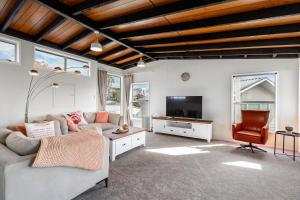 een woonkamer met 2 banken en een tv bij Couches, Bar Table & Kawau View in Snells Beach