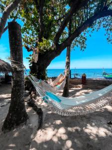 a hammock on the beach under trees at Cili Emas Oceanside Resort in Tejakula