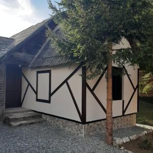 a large white and black garage with a tree at Cabana Mos in Statjunea Borsa