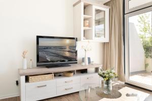 ein Wohnzimmer mit einem TV auf einem weißen Entertainment-Center in der Unterkunft Miramar Wohnung 312 in Grömitz