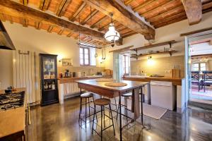 una gran cocina con una gran mesa de madera y taburetes en Villa Collina by PosarelliVillas, en Montegiove