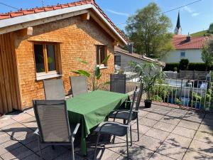 una mesa verde y sillas frente a una casa en Allgäu Hütten Loft - Großzügig - Terrasse, en Buchenberg