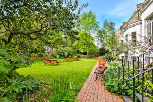 un parc avec des bancs et des tables dans l'herbe dans l'établissement Lee Abbey London, à Londres