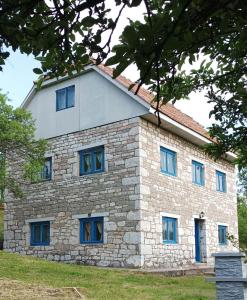 ein großes Steingebäude mit blauen Fenstern darauf in der Unterkunft Etno kuća Krvavac in Pljevlja