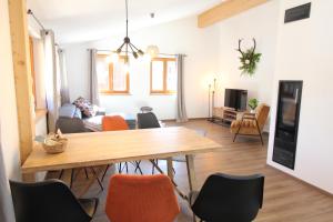 Allgäu Hütten Loft - Großzügig - Terrasse في Buchenberg: غرفة معيشة مع طاولة وكراسي خشبية