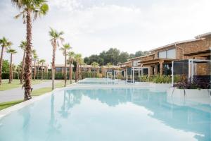 una piscina con palmeras y un edificio en Kallithea Village hotel, en Kallithea Halkidikis