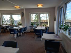 ein Restaurant mit Tischen und Stühlen und Fenstern in der Unterkunft Mein Vierjahreszeiten Hotel Garni Superior in Sankt Andreasberg