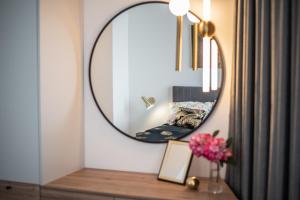 a mirror on a wall next to a table with flowers at Apartament Ogrodowy Władysławowo in Władysławowo