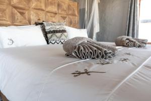 un letto bianco con due coperte e asciugamani sopra di Desert Homestead Lodge a Sesriem