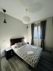 Schlafzimmer mit einem Bett mit einer schwarzen und weißen Bettdecke in der Unterkunft HOSPEDAJE CORREDOR DE HENARES in Torrejón de Ardoz