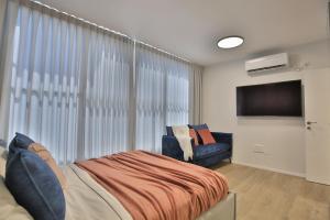 a bedroom with a bed and a flat screen tv at Cozy and stylish 1-bedroom apartment in Netanya