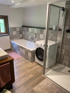 a bathroom with a tub and a washing machine at Ferienwohnung Lichterhof in Sebnitz