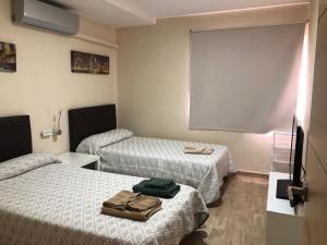 Apartamentos Albeniz في الجزيرة الخضراء: غرفه فندقيه سريرين وكيس على الطاوله