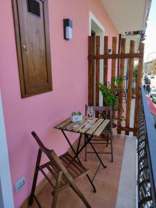 een tafel en stoelen op een balkon met een roze muur bij I dù Meli Apartments in Taormina