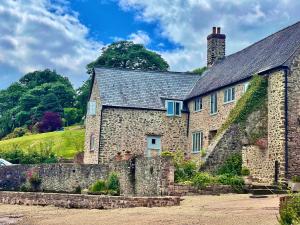 an old stone house with a stone wall at Slowley Farm Cottage in Luxborough