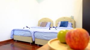 1 dormitorio con 2 camas y 1 manzana en una mesa en The Backyard Homestay, en Pak Chong
