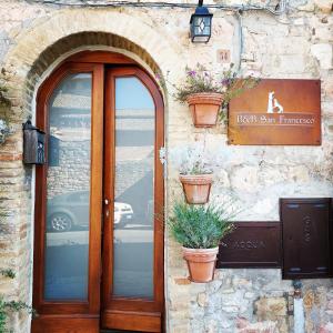 uma porta de um edifício com vasos de plantas sobre ele em B&B San Francesco em Assis