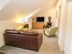sala de estar con sofá de cuero marrón y silla en Woodlands, en Keighley