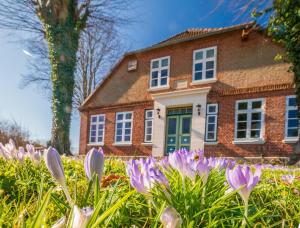 uma casa com flores roxas em frente em "Gästehaus Summersby" - Natururlaub mit exklusivem Landhausflair em Westfehmarn