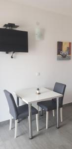 einen weißen Tisch mit 2 Stühlen und einen TV in der Unterkunft Apartman Nikolić 1 in Makarska