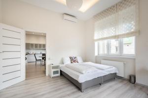 ein weißes Schlafzimmer mit einem Bett und einem Tisch in der Unterkunft Cascade Corvin Apartment in Budapest