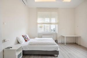 ein weißes Schlafzimmer mit einem Bett und einem Tisch in der Unterkunft Cascade Corvin Apartment in Budapest