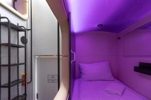 uma cama roxa num pequeno quarto com um tecto roxo em Capsule Hotel Constellation 89 em Lviv