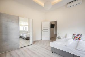 ein weißes Schlafzimmer mit einem Spiegel und einem Bett in der Unterkunft Cascade Corvin Apartment in Budapest