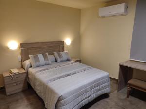 1 dormitorio con 1 cama grande con sábanas y almohadas blancas en Hotel Novo en Ponferrada