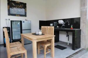 uma cozinha com uma mesa e cadeiras de madeira e uma secretária em Rara Guesthouse em Canggu