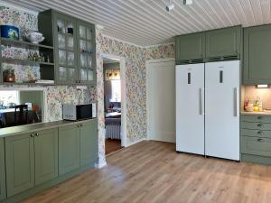 a kitchen with green cabinets and a white refrigerator at Bolmen Bed - Vandrarhem in Ljungby
