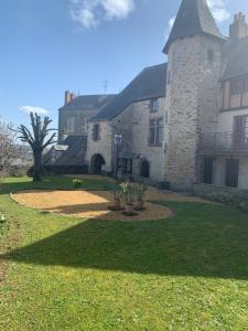 a large stone building with a grass yard at Le logis du Vassal in Laval