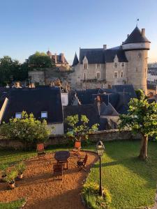 a park with chairs and a table in front of a castle at Le logis du Vassal in Laval