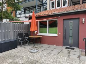 ein rotes Haus mit einem Tisch und einem Regenschirm in der Unterkunft Ferienwohnung Northeim City in Northeim