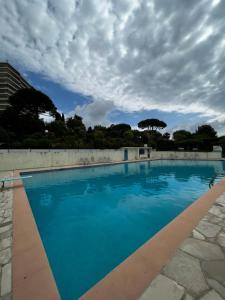 a large blue swimming pool with a cloudy sky at Studio with a panoramic view at the last floor of the residence with a pool in Antibes
