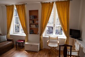 sala de estar con sofá y 2 ventanas en Appartement place Des Cordeliers, en Dinan