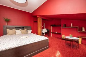 1 dormitorio con paredes rojas, 1 cama y 1 mesa en Odzieżowa Apartment en Elblag