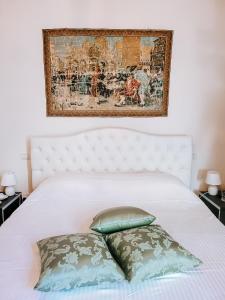 ein weißes Bett mit zwei Kissen und ein Gemälde darüber in der Unterkunft Casa Locatelli - Apartment Deluxe & Suite in Padua