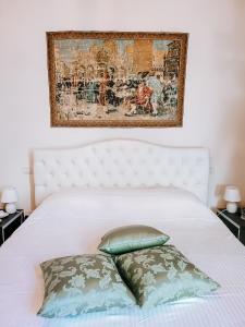 un letto bianco con due cuscini e un dipinto sopra di esso di Casa Locatelli - Apartment Deluxe & Suite a Padova