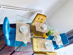 a table with a blue chair and a table with plates at Mayfair Place - Cosy 3 Bedroom House with Free Parking in Birmingham