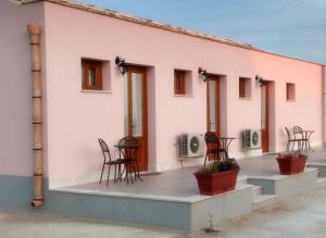 un edificio rosa con sillas en un patio en Baglio Antico, en Fulgatore