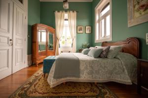 um quarto com uma cama com paredes verdes e uma janela em Palacete Villa Idalina em Caminha mais 37 fotografias