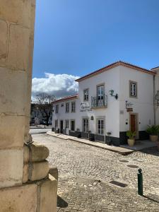 a cobblestone street in front of a white building at Largo da Rainha, Guesthouse in Merciana