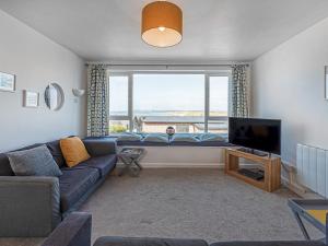 a living room with a couch and a large window at Pass the Keys Sea View Apartment in centre of Rhosneigr in Rhosneigr