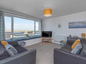 Una sala de estar con un sofá y una ventana grande. en Sea View Apartment in centre of Rhosneigr - Pass the Keys, en Rhosneigr