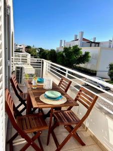 a wooden table and chairs on a balcony at Cabanas Wonder - 150mts from the beach in Cabanas de Tavira